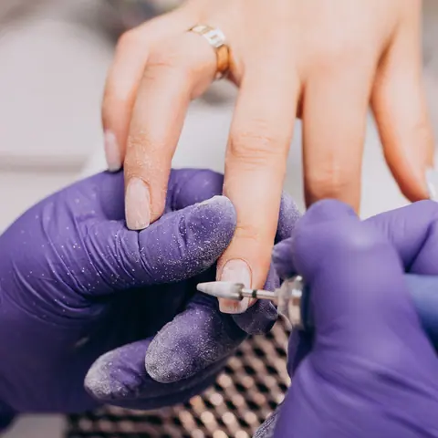 Manicure com esmaltação e luvas roxas